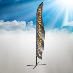 Oriflamme publicitaire personnalisé avec le texte ‘agence-dcc.fr’ sur un fond de ciel ensoleillé