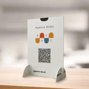 PLV de comptoir pour Agence D&C, avec leur logo, un code QR et l’URL du site web, illustrant un article sur la préparation d’un salon professionnel.