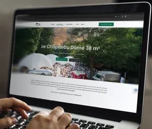 Mains tapant sur un ordinateur portable affichant le site web tent-action.fr, conçu par l’agence DC&C. Tent'action spécialisé dans la location de chapiteaux dômes disponible Département 40, 33, 64